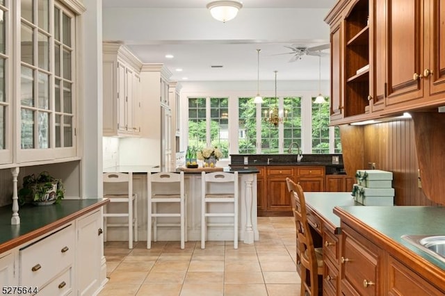 kitchen with dark countertops, open shelves, brown cabinetry, and light tile patterned flooring