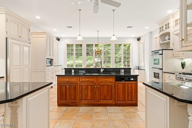 kitchen featuring stainless steel appliances, hanging light fixtures, light tile patterned flooring, a sink, and dark stone counters