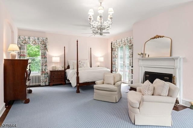 bedroom featuring multiple windows, a fireplace, radiator heating unit, and an inviting chandelier