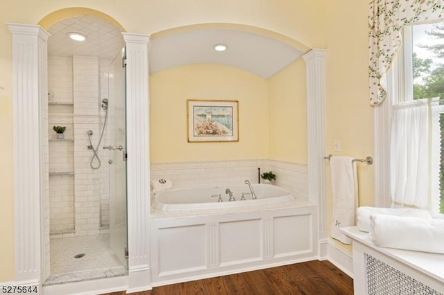 full bathroom featuring wood finished floors, a stall shower, a garden tub, and ornate columns