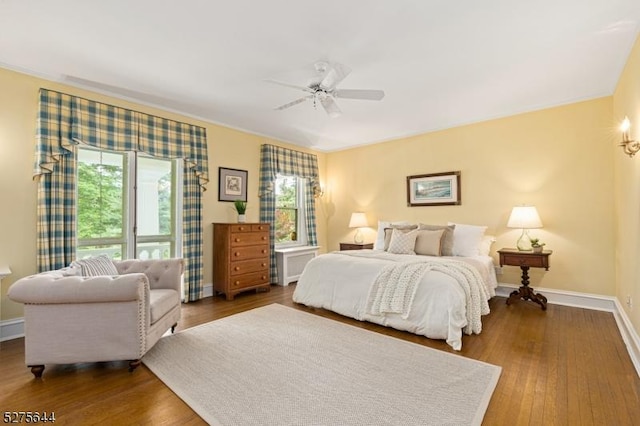 bedroom with dark wood-style floors, baseboards, a ceiling fan, and ornamental molding