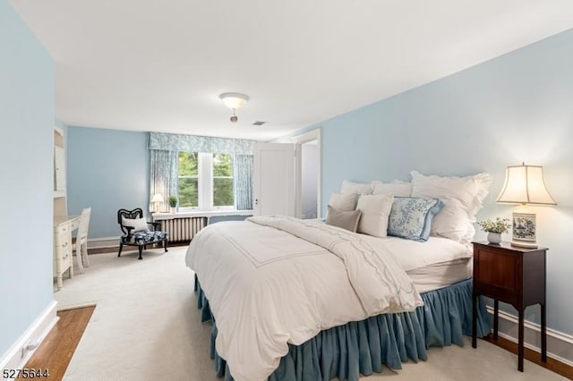 bedroom featuring radiator, visible vents, baseboards, and wood finished floors