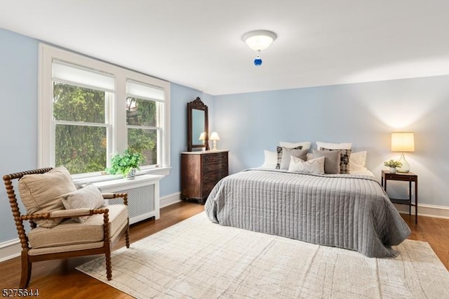 bedroom with radiator, baseboards, and wood finished floors