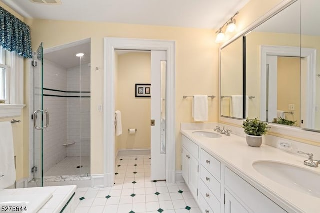 bathroom featuring double vanity, a stall shower, a sink, and tile patterned floors