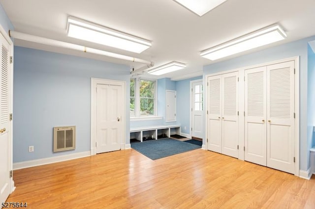 interior space with baseboards, light wood-style flooring, and heating unit