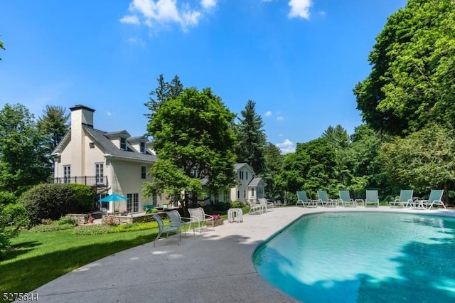 outdoor pool featuring a lawn, a patio area, and fence