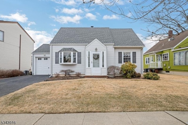 cape cod house with driveway, a shingled roof, central AC unit, an attached garage, and a front yard