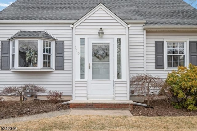 doorway to property with a shingled roof