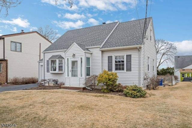 view of front of house featuring a shingled roof and a front yard