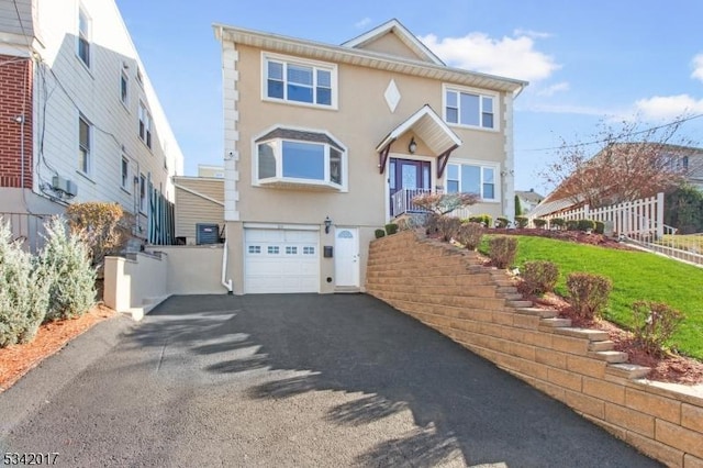 view of front of house featuring a garage, fence, driveway, and stucco siding