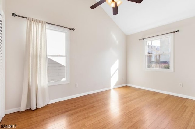 spare room featuring high vaulted ceiling, light wood-style floors, baseboards, and a ceiling fan