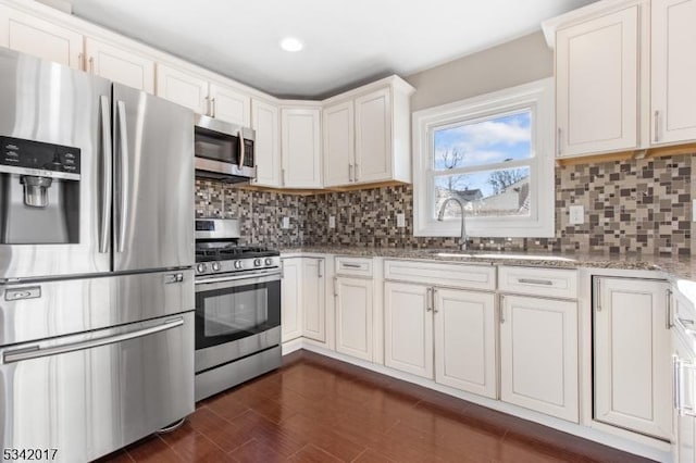 kitchen featuring decorative backsplash, dark wood-style floors, light stone counters, stainless steel appliances, and a sink