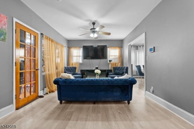 living area featuring wood finished floors, a ceiling fan, and baseboards