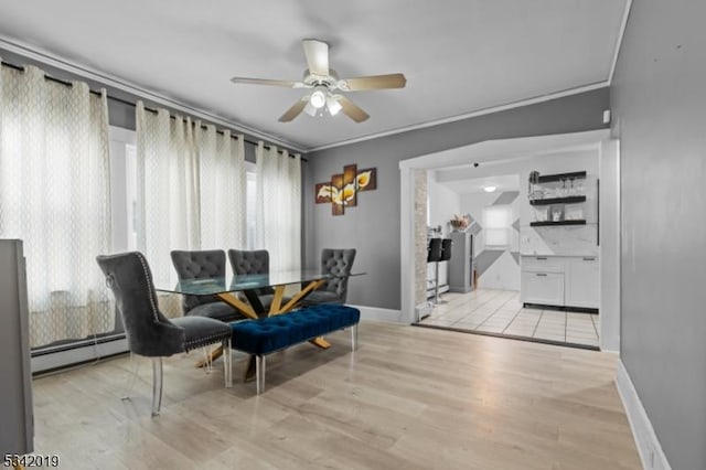 sitting room with a baseboard heating unit, ornamental molding, light wood-style flooring, and baseboards