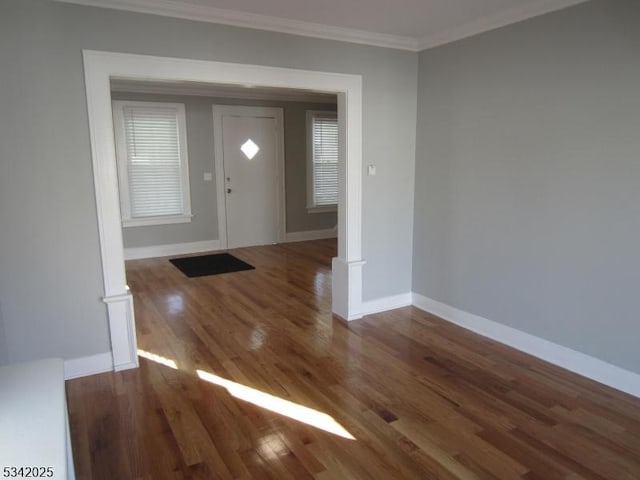 foyer entrance featuring baseboards, wood finished floors, and crown molding