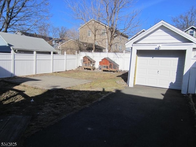 view of yard with a garage, driveway, an outbuilding, and fence