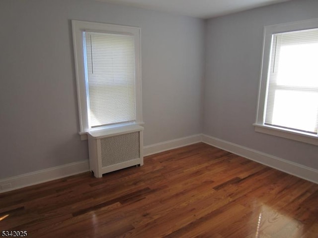 unfurnished room featuring radiator, baseboards, and wood finished floors