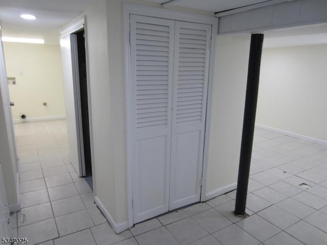 corridor featuring recessed lighting, baseboards, and light tile patterned floors