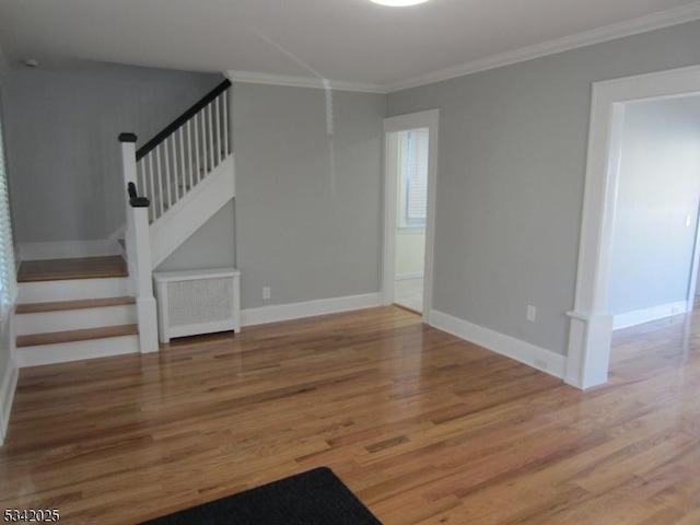 unfurnished living room with stairs, ornamental molding, wood finished floors, and baseboards