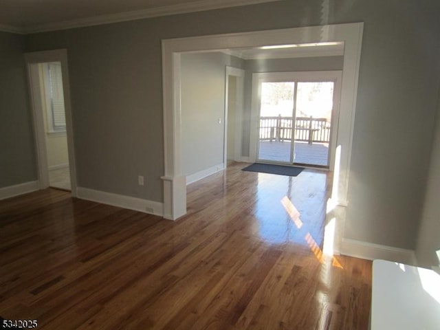 unfurnished room featuring crown molding, baseboards, and wood finished floors