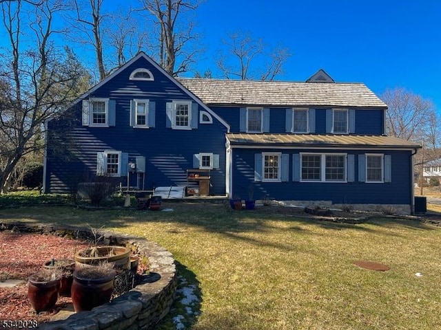 rear view of property with a standing seam roof, metal roof, and a yard