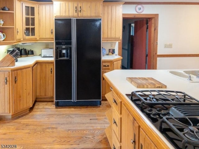 kitchen with glass insert cabinets, black appliances, light countertops, and light wood-style floors