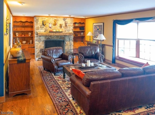 living area with a fireplace, wood-type flooring, and ornamental molding