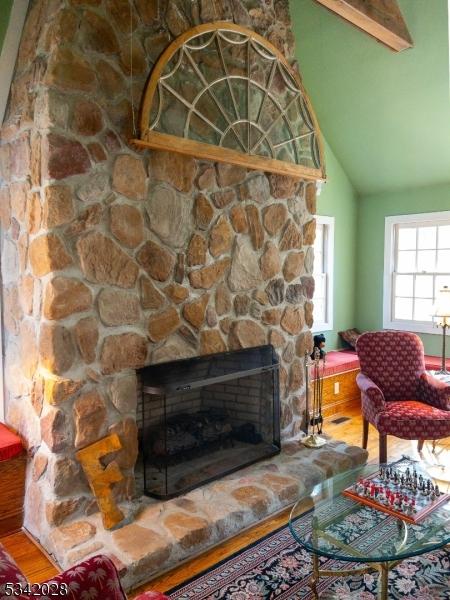 living area with wood finished floors, a fireplace, and vaulted ceiling