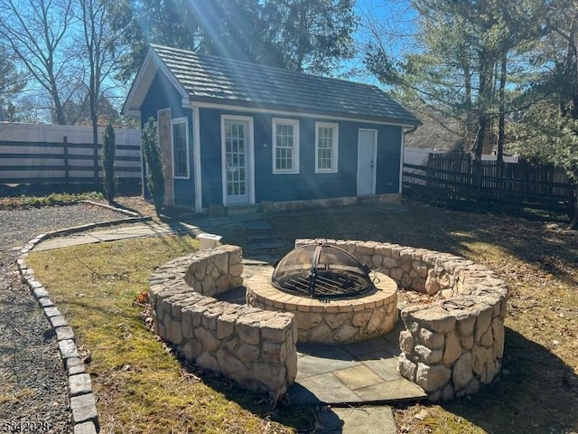 view of outbuilding featuring an outbuilding, a fenced backyard, and an outdoor fire pit