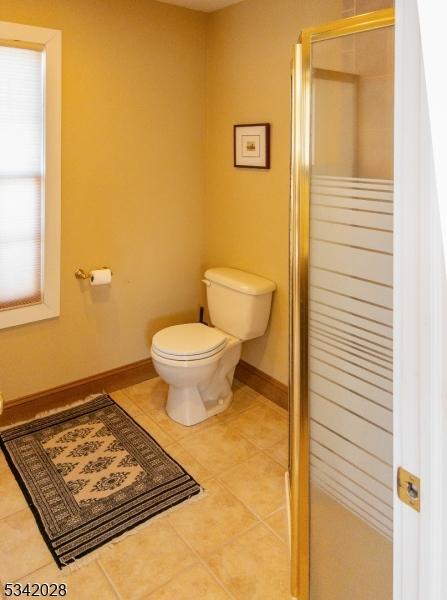 full bathroom with tile patterned floors, a stall shower, toilet, and baseboards