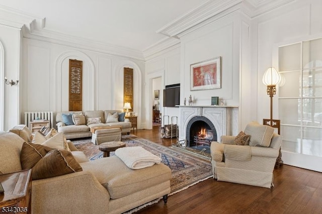 29 Kitchell Rd, Morris Twp, NJ 07960 - living room featuring dark wood-style floors, radiator heating unit, ornamental molding, a lit fireplace, and arched walkways