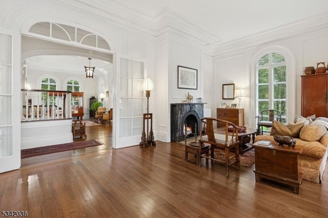 29 Kitchell Rd, Morris Twp, NJ 07960 - living area featuring a decorative wall, wood finished floors, a warm lit fireplace, crown molding, and arched walkways