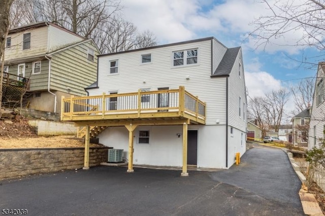 back of property with aphalt driveway, stairway, a wooden deck, and central AC unit