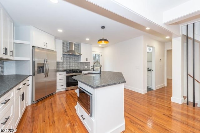 kitchen with light wood-style flooring, a sink, appliances with stainless steel finishes, wall chimney range hood, and open shelves