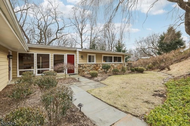 ranch-style house with stone siding and a front lawn