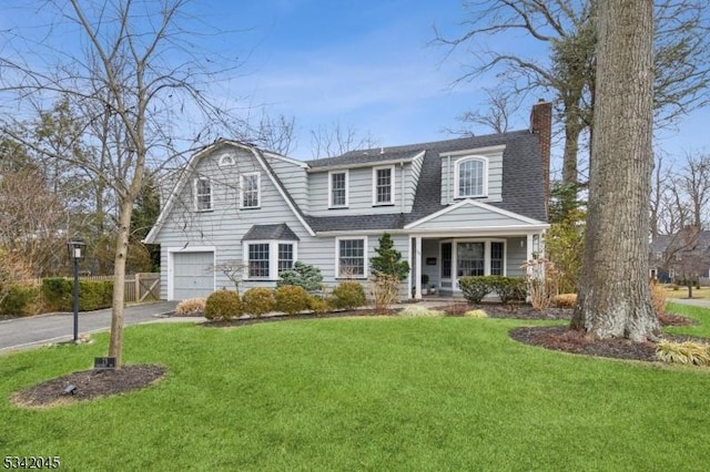 view of front facade featuring a chimney, a shingled roof, fence, driveway, and a front lawn