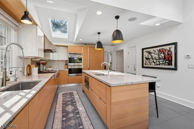 kitchen featuring double oven, a skylight, exhaust hood, light brown cabinetry, and modern cabinets