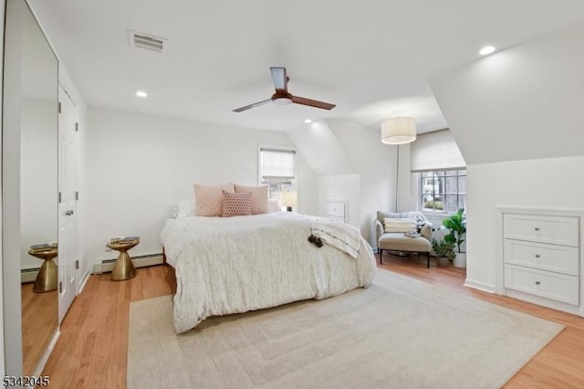 bedroom with light wood-style floors, a baseboard radiator, visible vents, and multiple windows