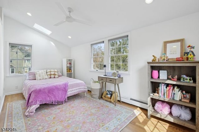 bedroom featuring vaulted ceiling with skylight, multiple windows, a baseboard radiator, and wood finished floors