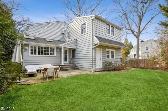 rear view of house with a yard, roof with shingles, a patio area, and fence