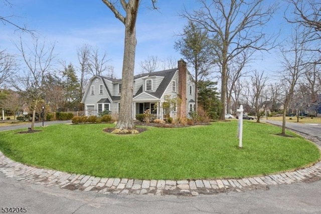 view of front of property featuring a front yard, a chimney, and a gambrel roof