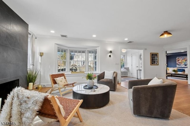 living room with recessed lighting, ornamental molding, a wealth of natural light, and a tile fireplace