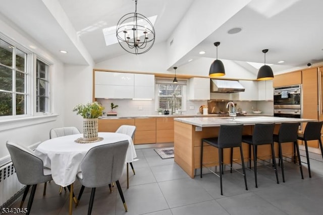 kitchen featuring a center island with sink, lofted ceiling, modern cabinets, ventilation hood, and light countertops