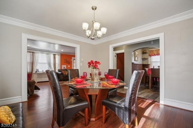 dining space with arched walkways, dark wood-style flooring, and crown molding