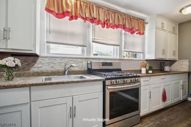 kitchen with backsplash, gas stove, a sink, and white cabinetry