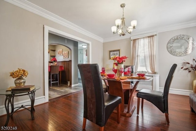 dining space with ornamental molding, wood-type flooring, baseboards, and an inviting chandelier