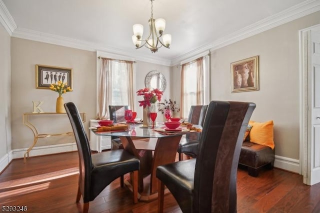 dining space featuring a chandelier, ornamental molding, wood finished floors, and baseboards