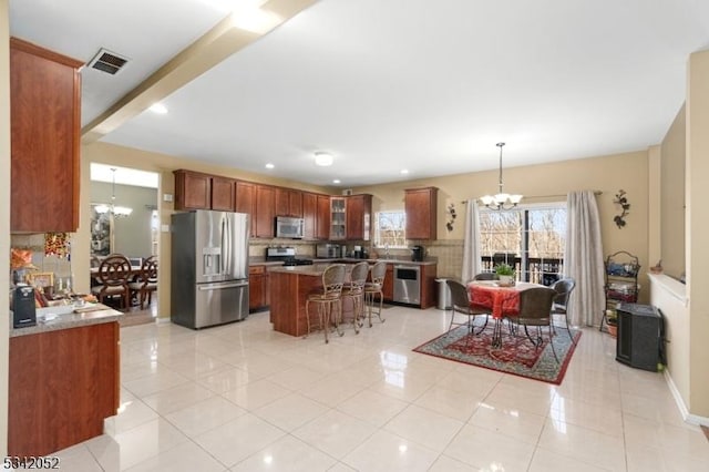 kitchen with a chandelier, stainless steel appliances, a kitchen bar, and light tile patterned flooring