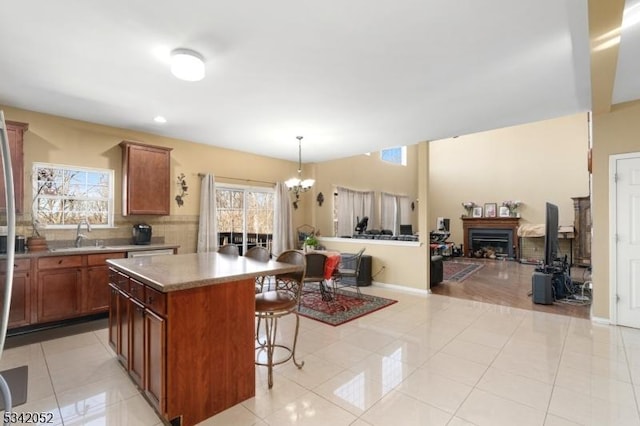 kitchen featuring a breakfast bar, light tile patterned flooring, a sink, open floor plan, and backsplash