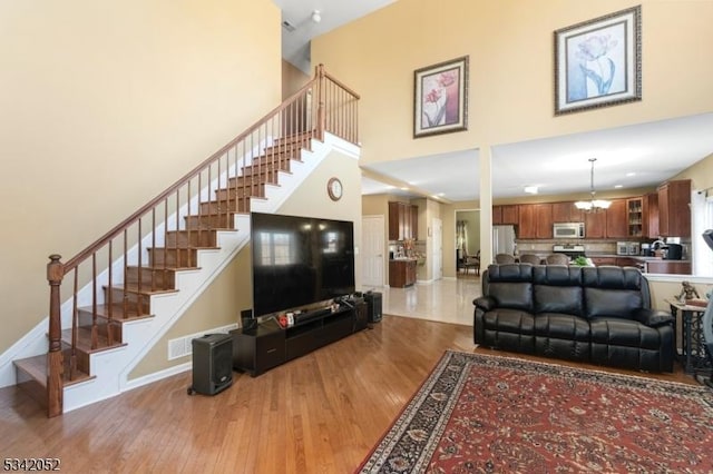 living area featuring stairway, baseboards, wood finished floors, and a chandelier